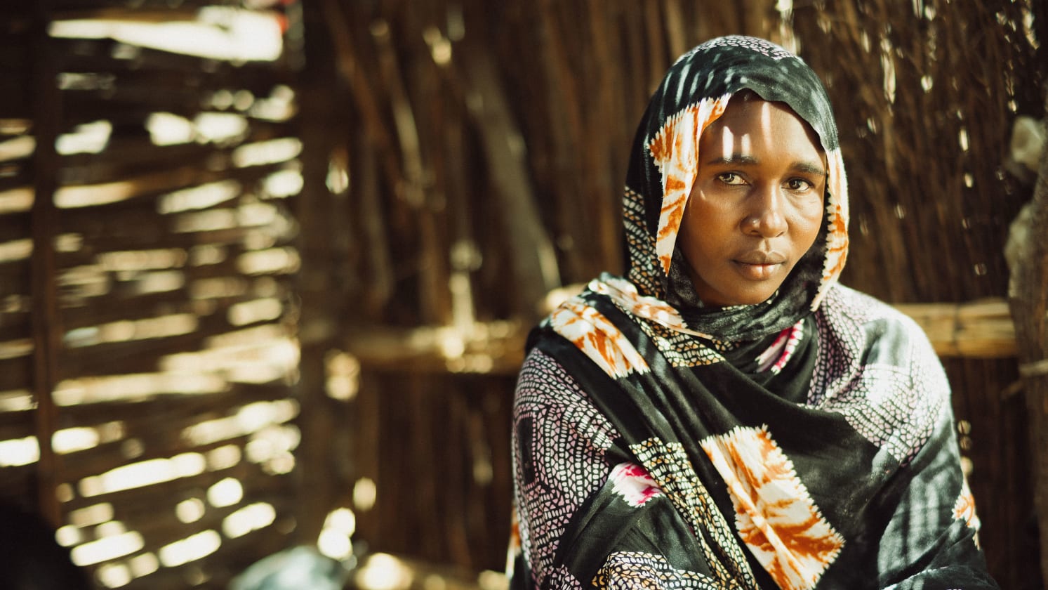 A close up of a woman dressed in a headscarf, looking directly at the camera.