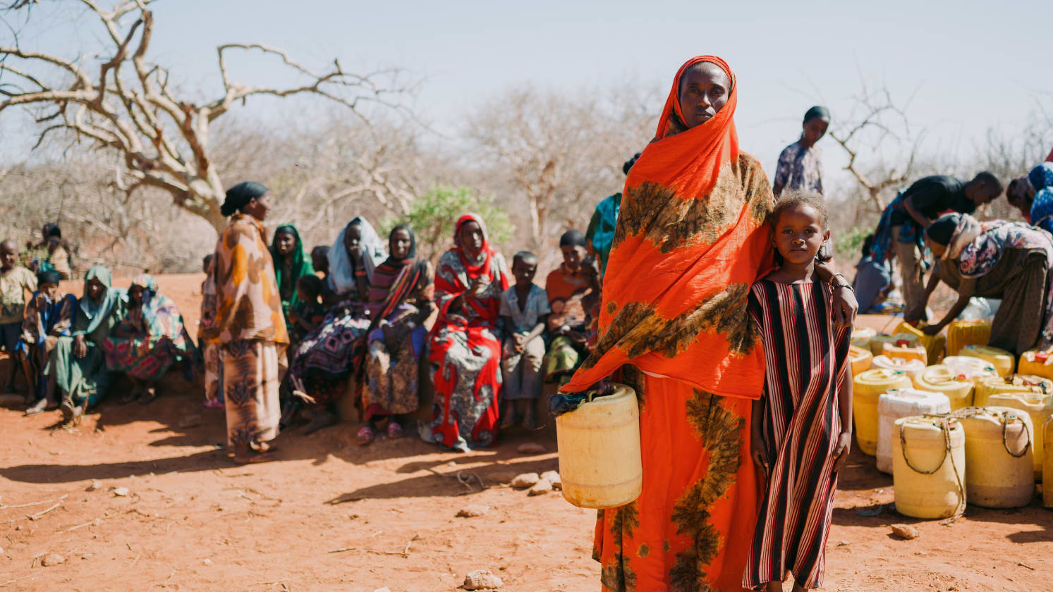 A mother and daughter standing next to each other, holding a container of water.