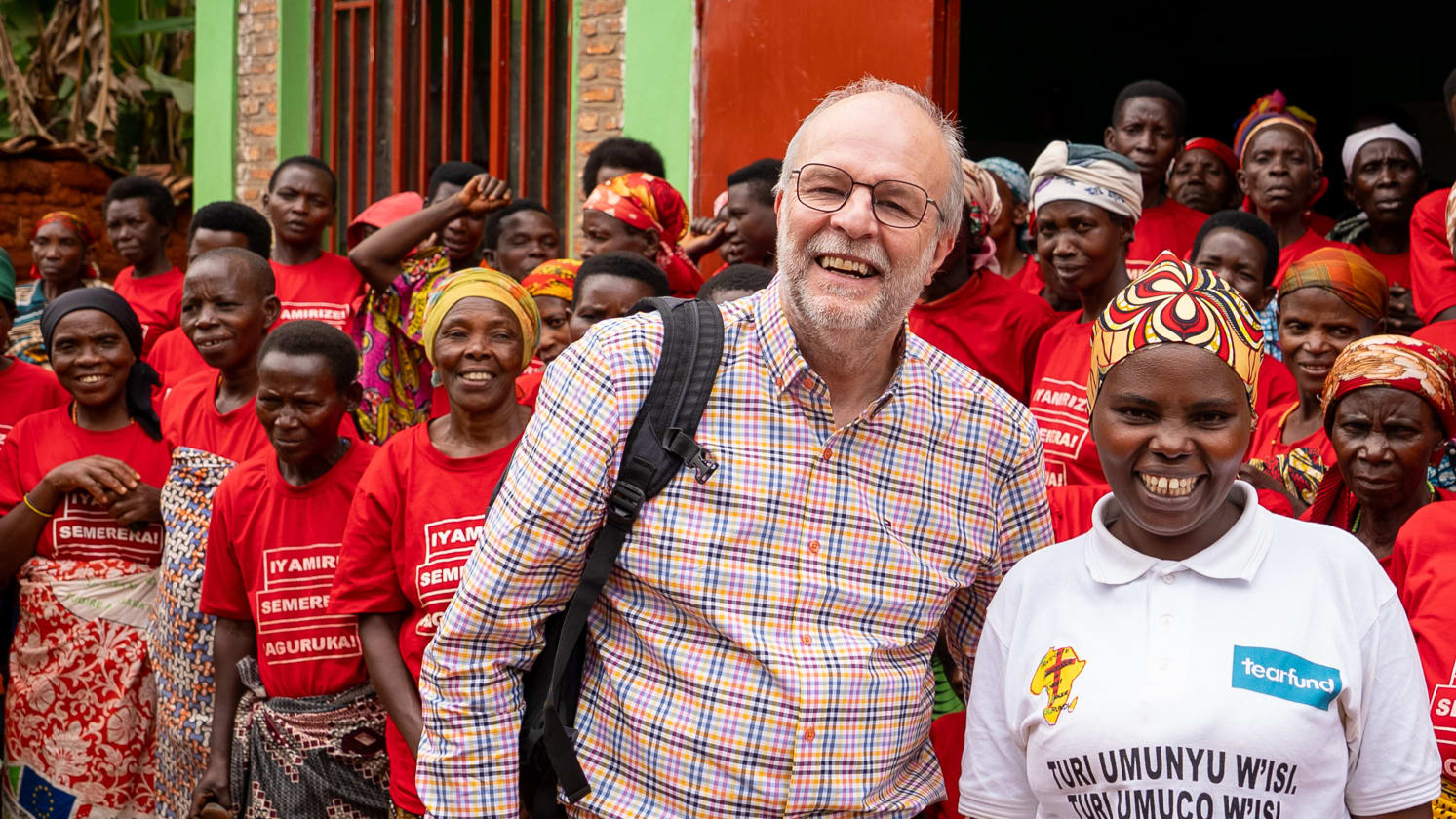 Group photo with a smiling white man and a smiling African woman in front of a crowd.