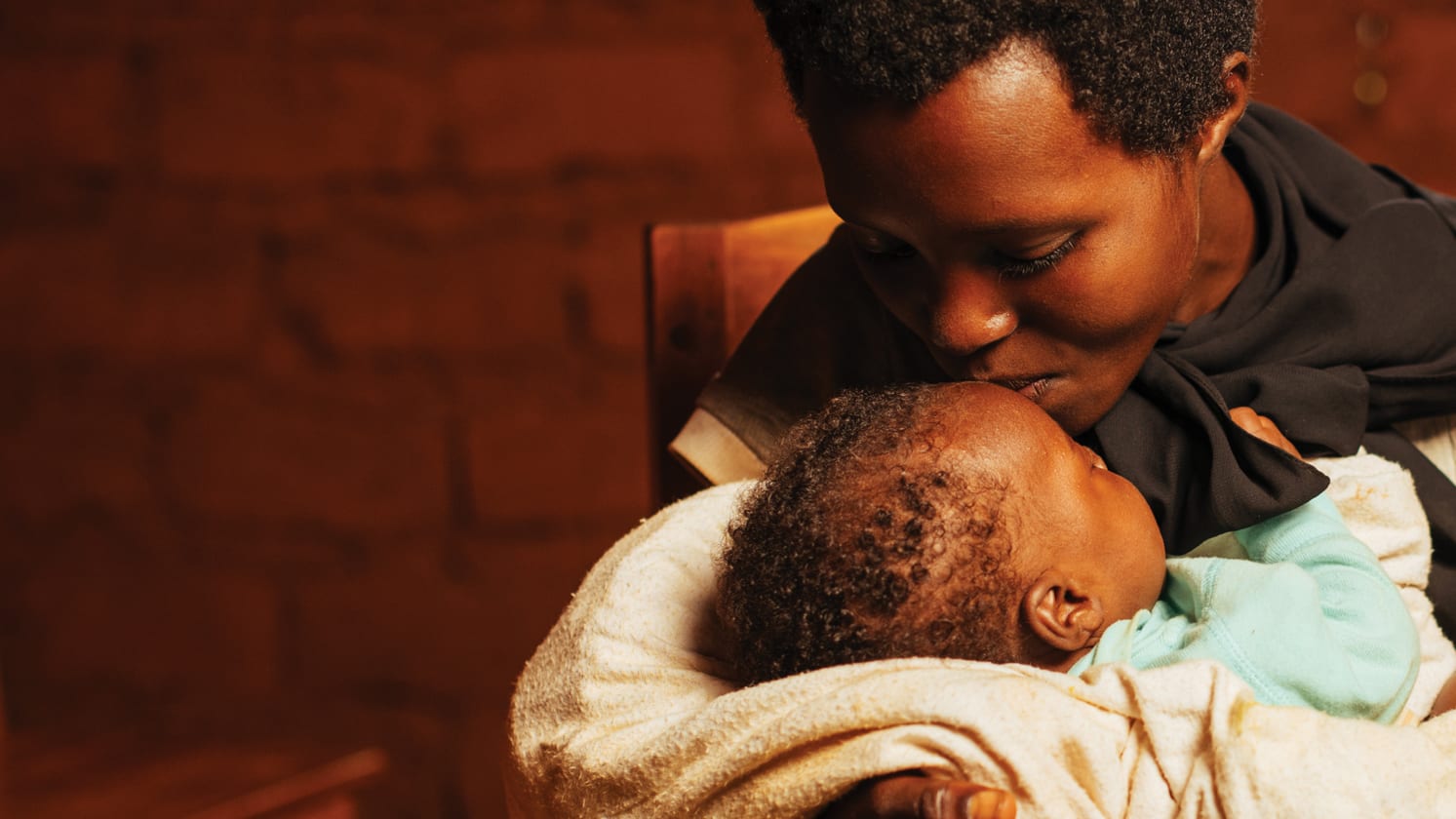 Close up of a woman holding a baby and kissing it on its forehead