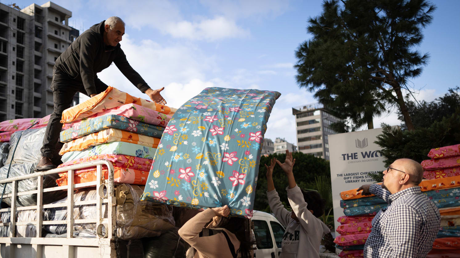 People unload floral mattresses from a truck. Some people are grabbing the mattresses.