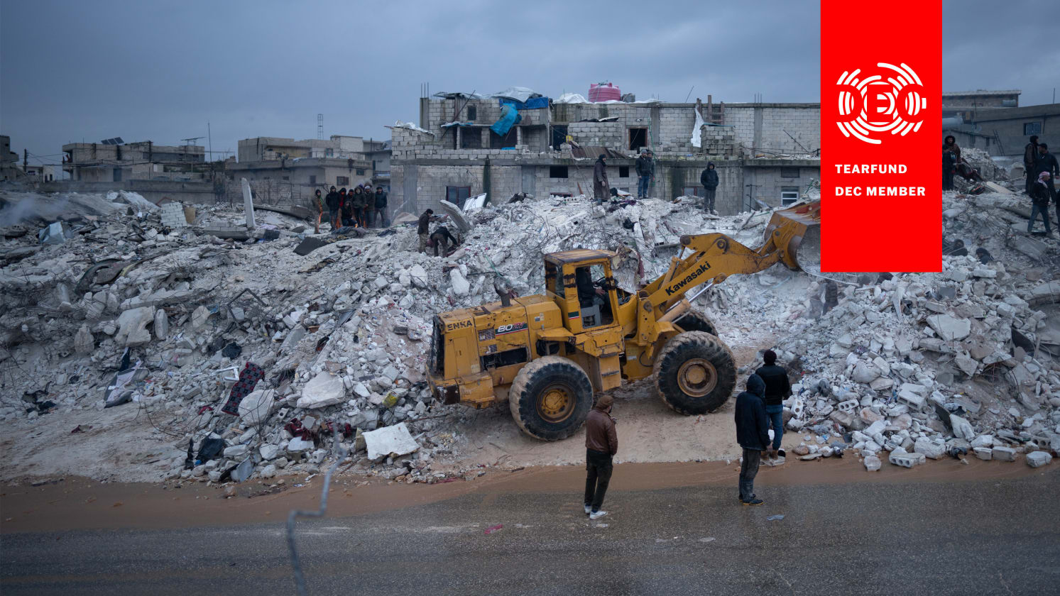 Groups of people standing on and around rubble with buildings in the background