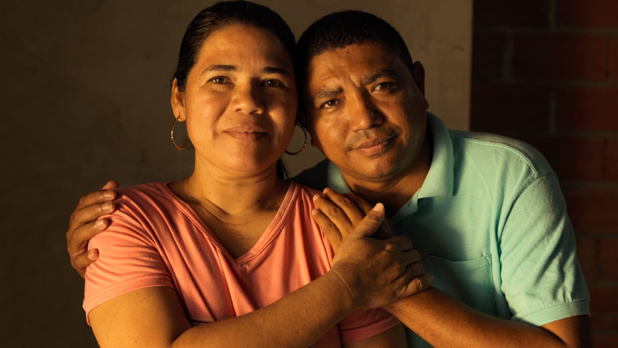 Una amorosa pareja colombiana de pie en el interior mirando a la cámara.