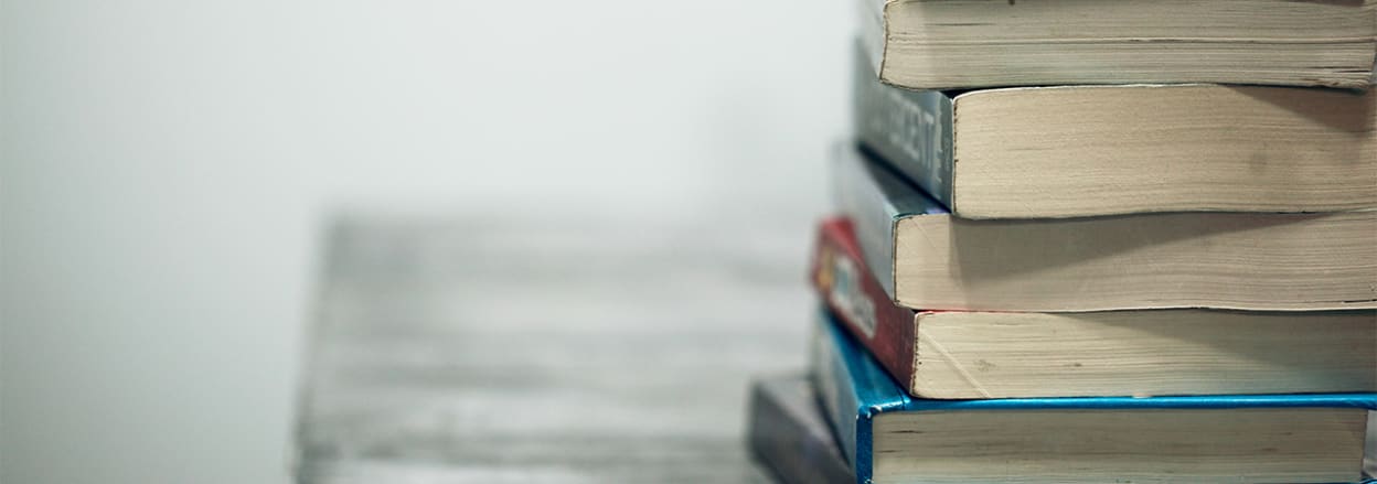 Pile of books on desk (Unsplash)