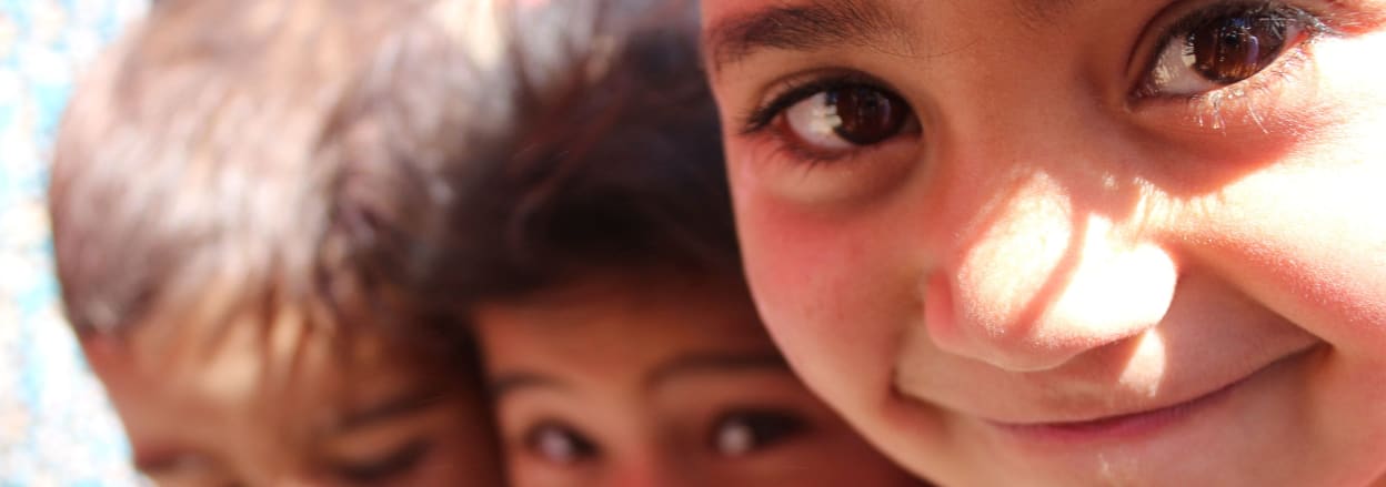 Three children play in an informal tent settlement in the Bekaa valley, Lebanon.