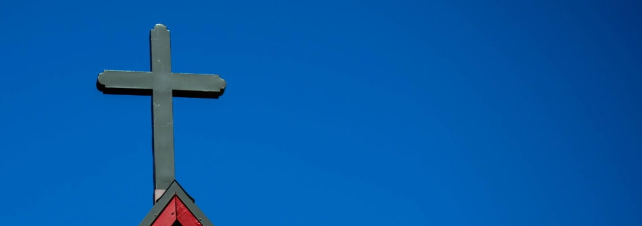 Cross on church roof against blue sky