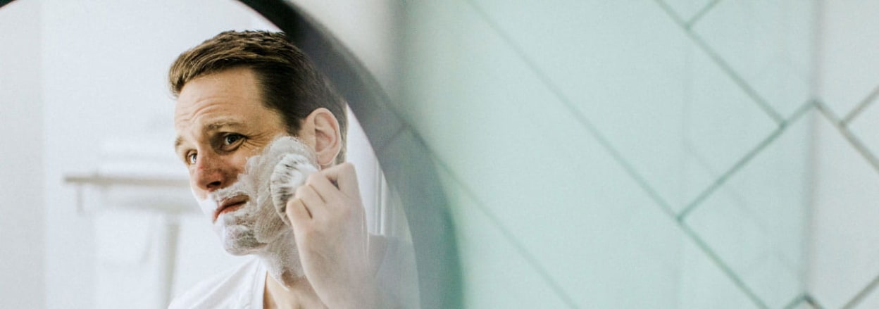 Man shaving in mirror.