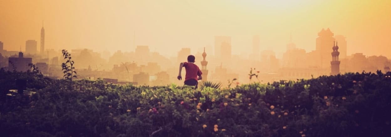 boy running across hill towards Cairo skyline