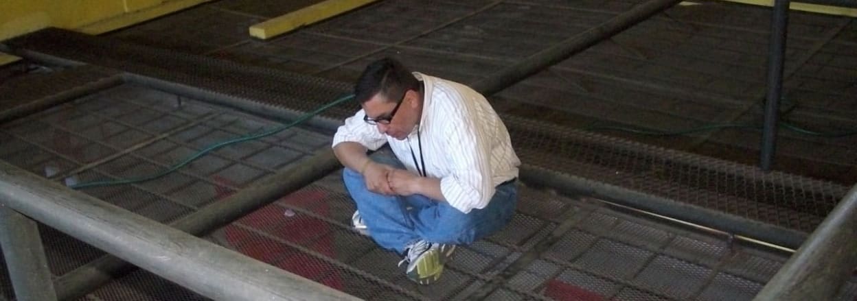 William on top of prison cage, speaking to the prisoners