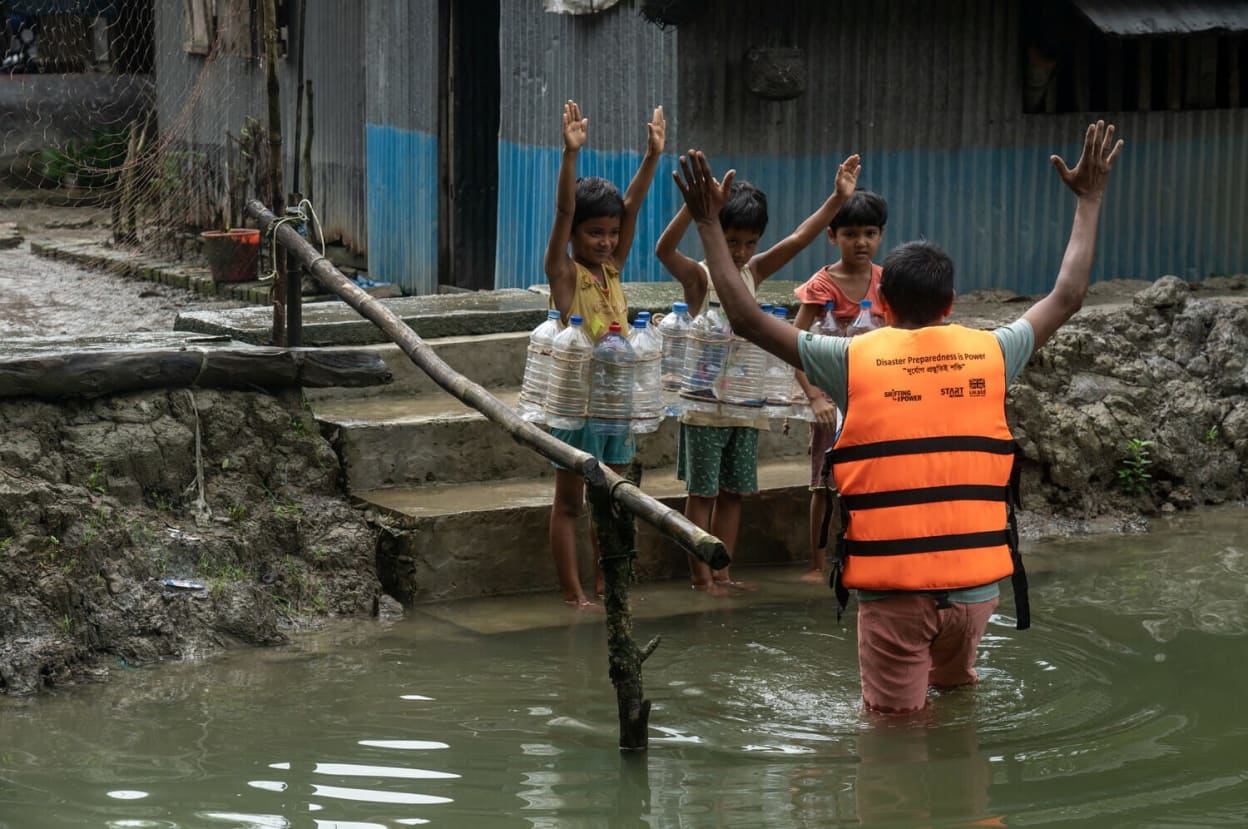 Children wearing life jackets made from plastic bottles enjoy a swimming lesson