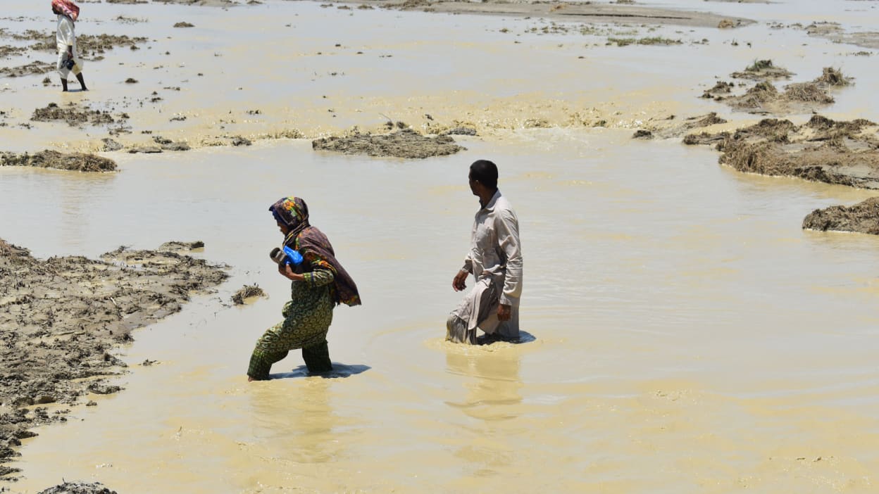 Two people wading through flood waters