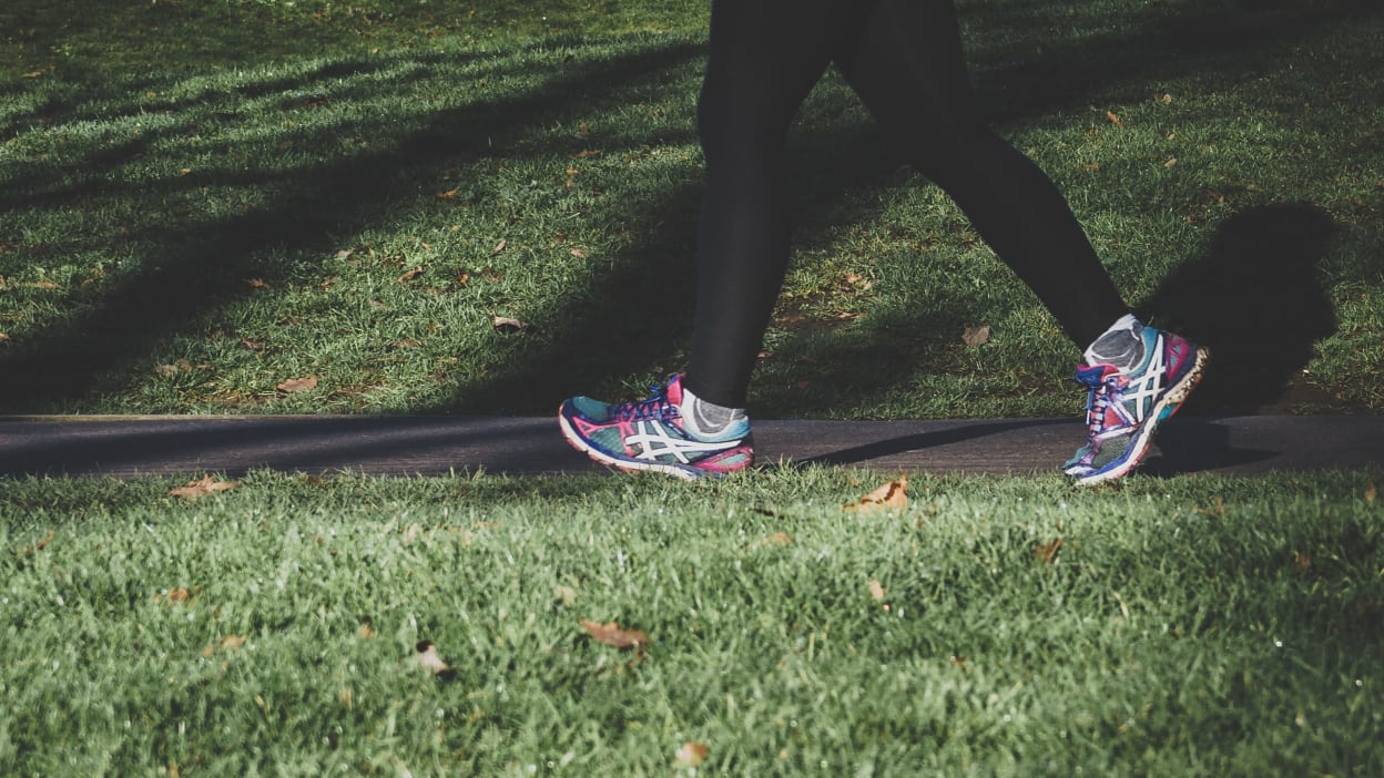 A person wearing trainers walking along a path.