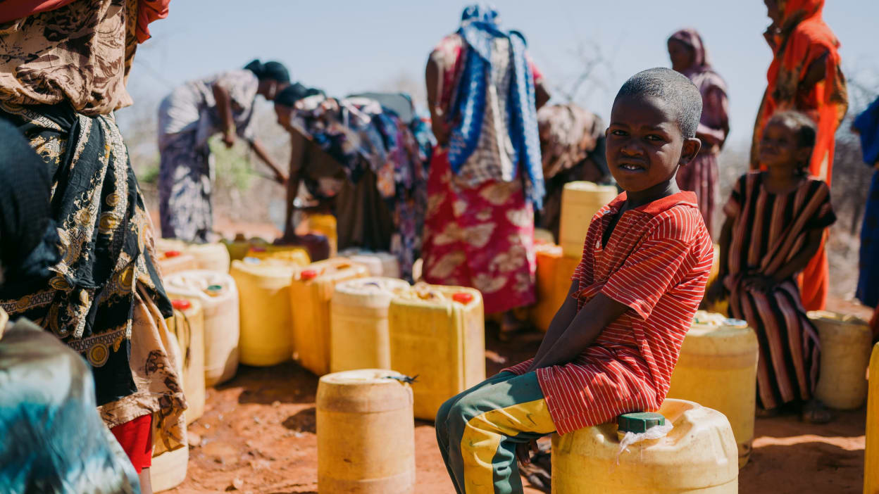 A child sat on a container of water.