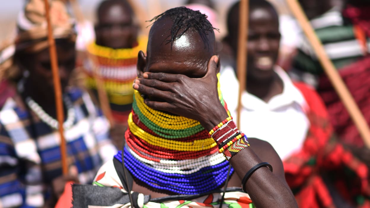 A woman covering her eyes to hide her tears as she talks about the devastating situation people in the region are facing.