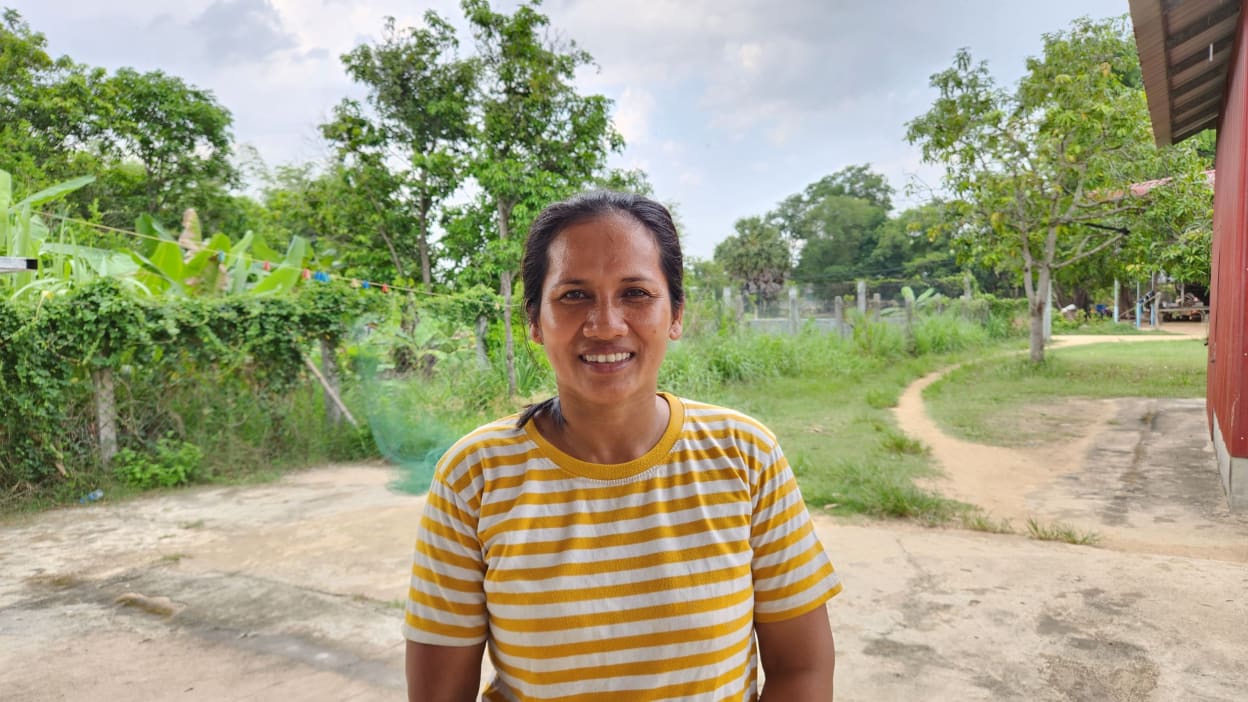 Saren, a mother in Cambodia, smiles at the camera. She has transformed her life through Bible study-based training facilitated by Tearfund's local church partners.