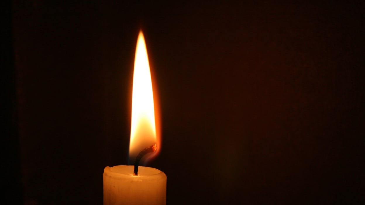 A single candle shines in the darkness