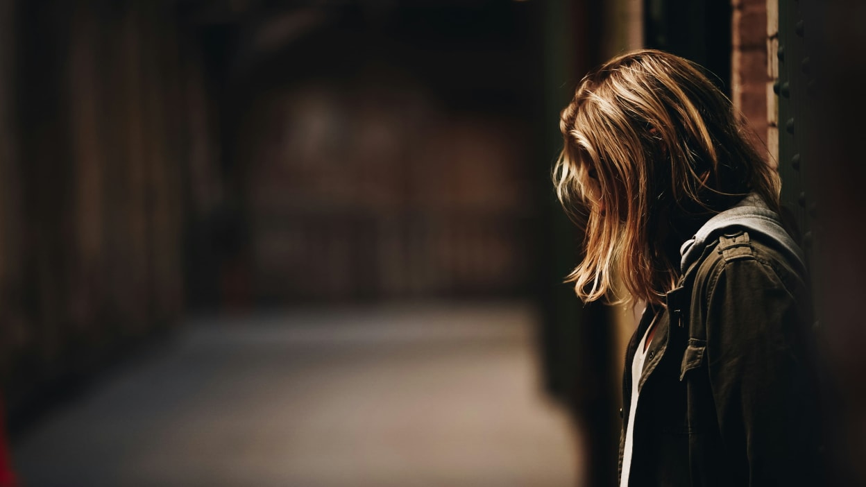 A woman stands in a dark corridor.