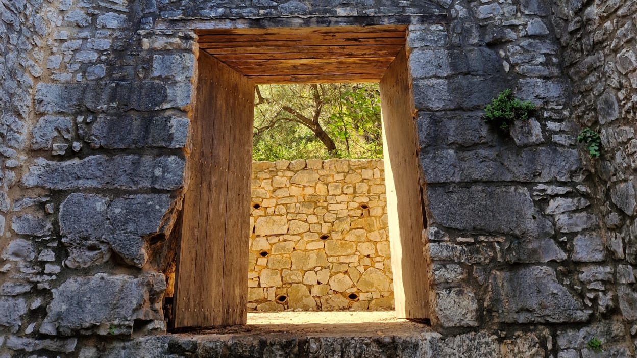 Light shines through a doorway in an ancient wall.