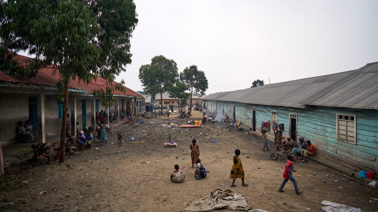 People move around outside between classrooms where they have sought shelter after having to flee the conflict