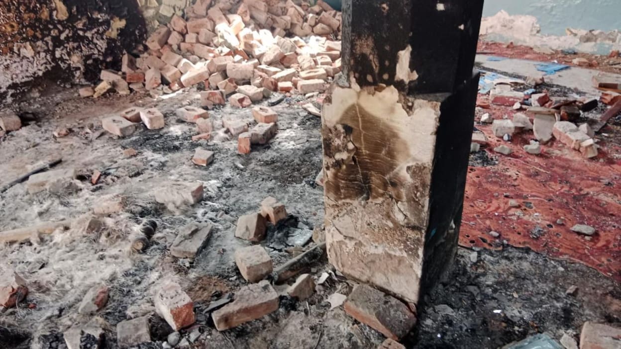 Rubble and burnt debris inside the remains of a building.