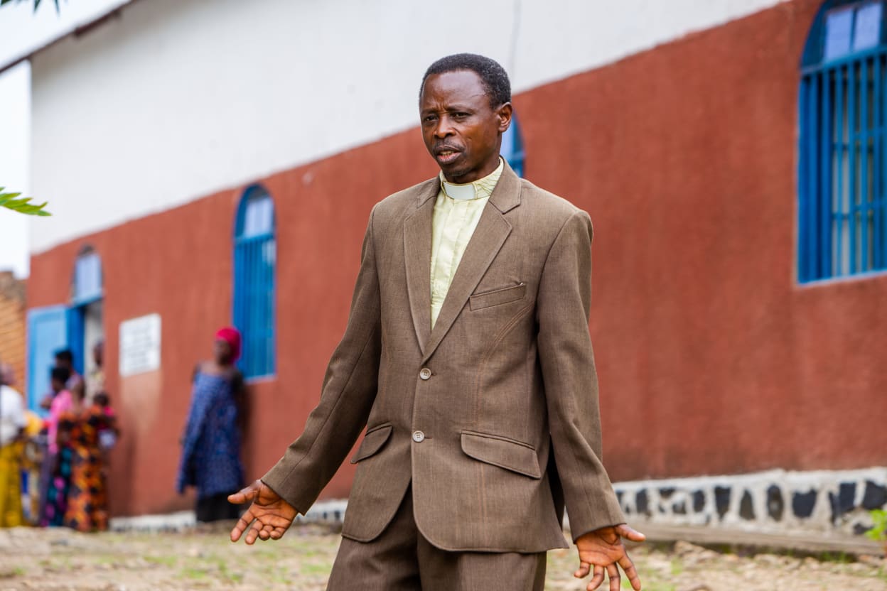 Pastor Ngendahimana Sarthiel from Burundi, who featured in the Tearfund DRTV advertisement, standing in front of the church in his community