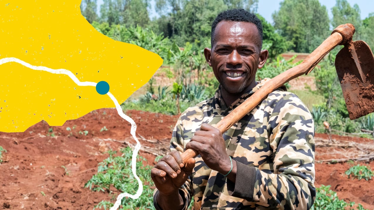 A smiling man holding a garden hoe