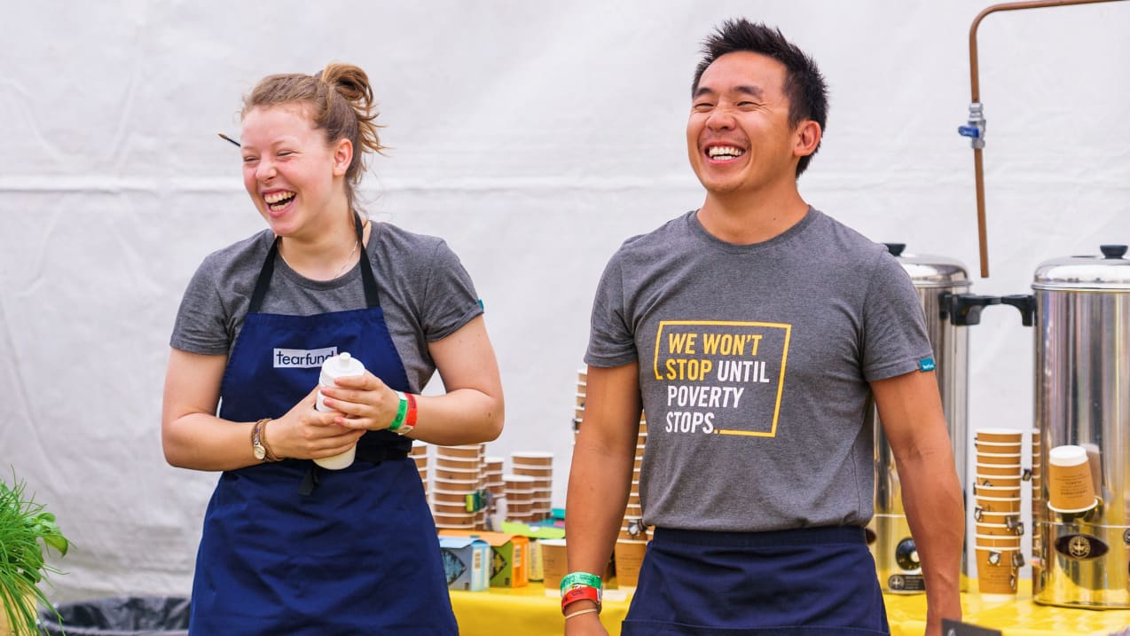 A man and a woman are stood in a cafe laughing