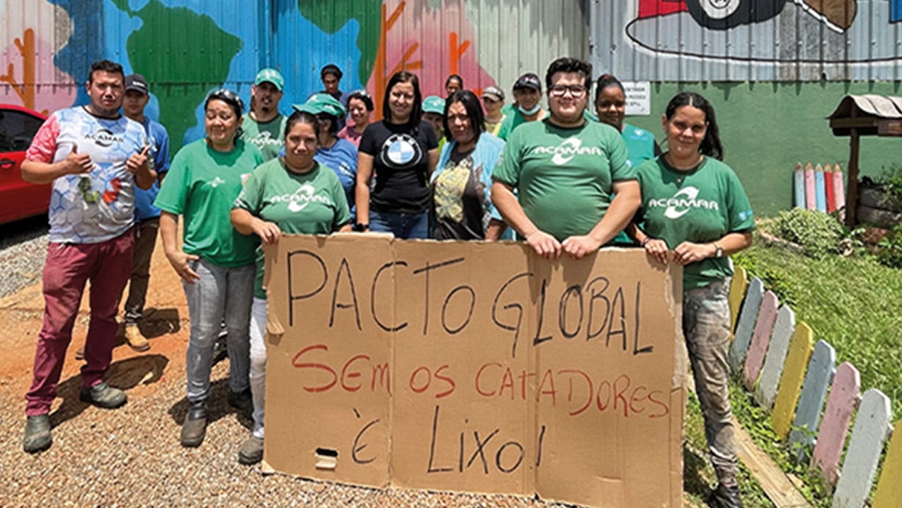 A group of people standing together, holding a cardboard sign