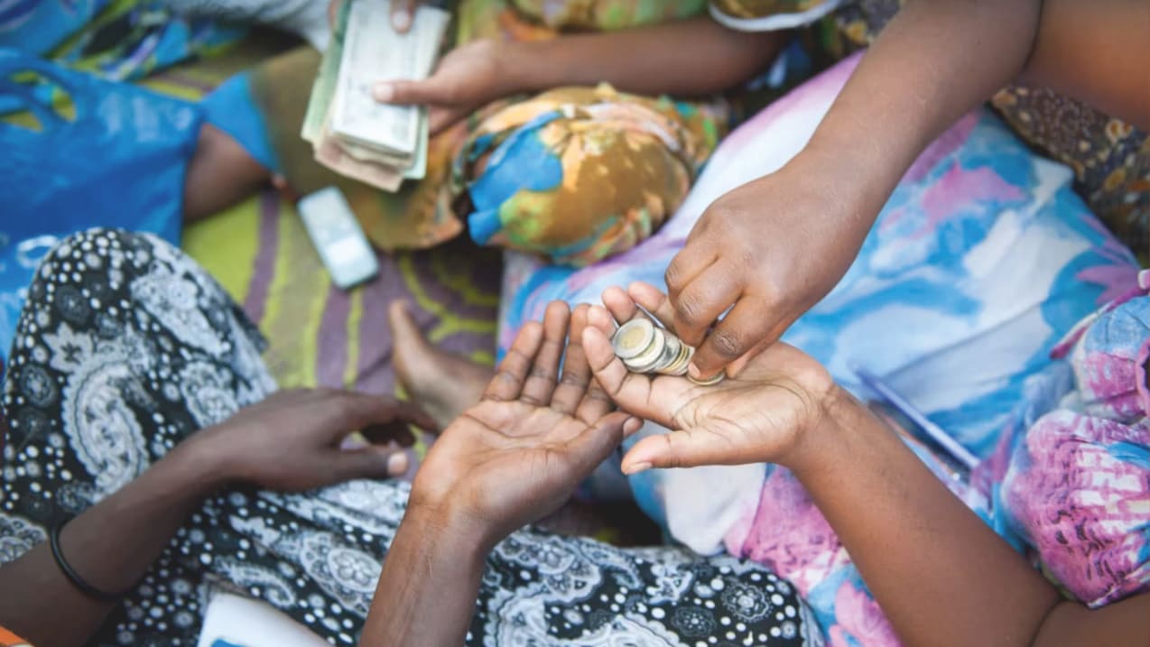 Close-up of hands exchanging money, including banknotes and coins.