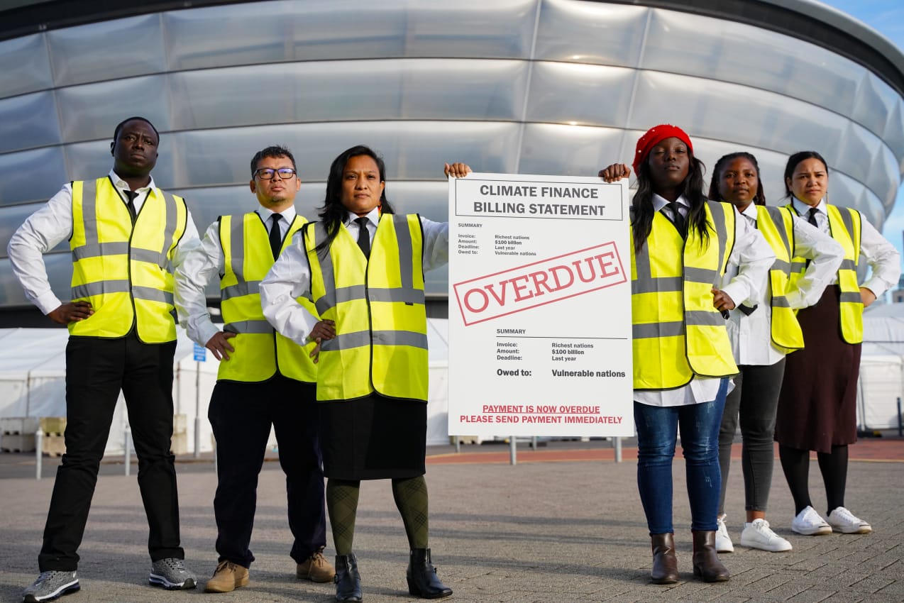 Climate activists from four continents take on the guise of bailiffs a COP26, dressed in high-vis jackets and holding a giant, unpaid-bill notice. They are issuing a final 'invoice' to the richest, most polluting countries, and calling on them to deliver on their promise of 2009 to jointly deliver $100 billion a year in climate finance by 2020. This payment is now overdue. Glasgow, COP26