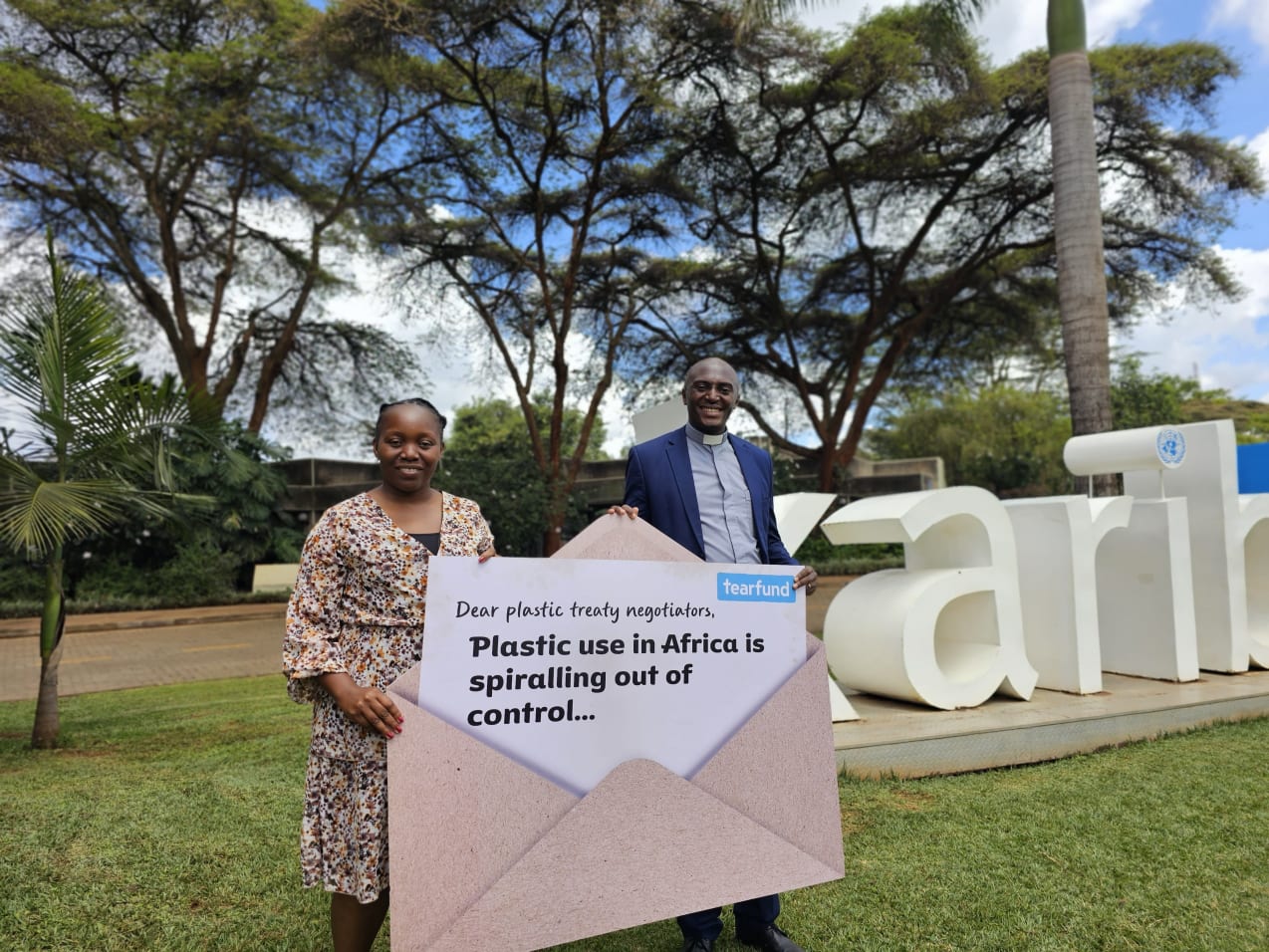 A woman and a man stand outside, jointly holding a large envelope which reads: "Dear plastic treaty negotiators, Plastic use in Africa is spiralling out of control..."
