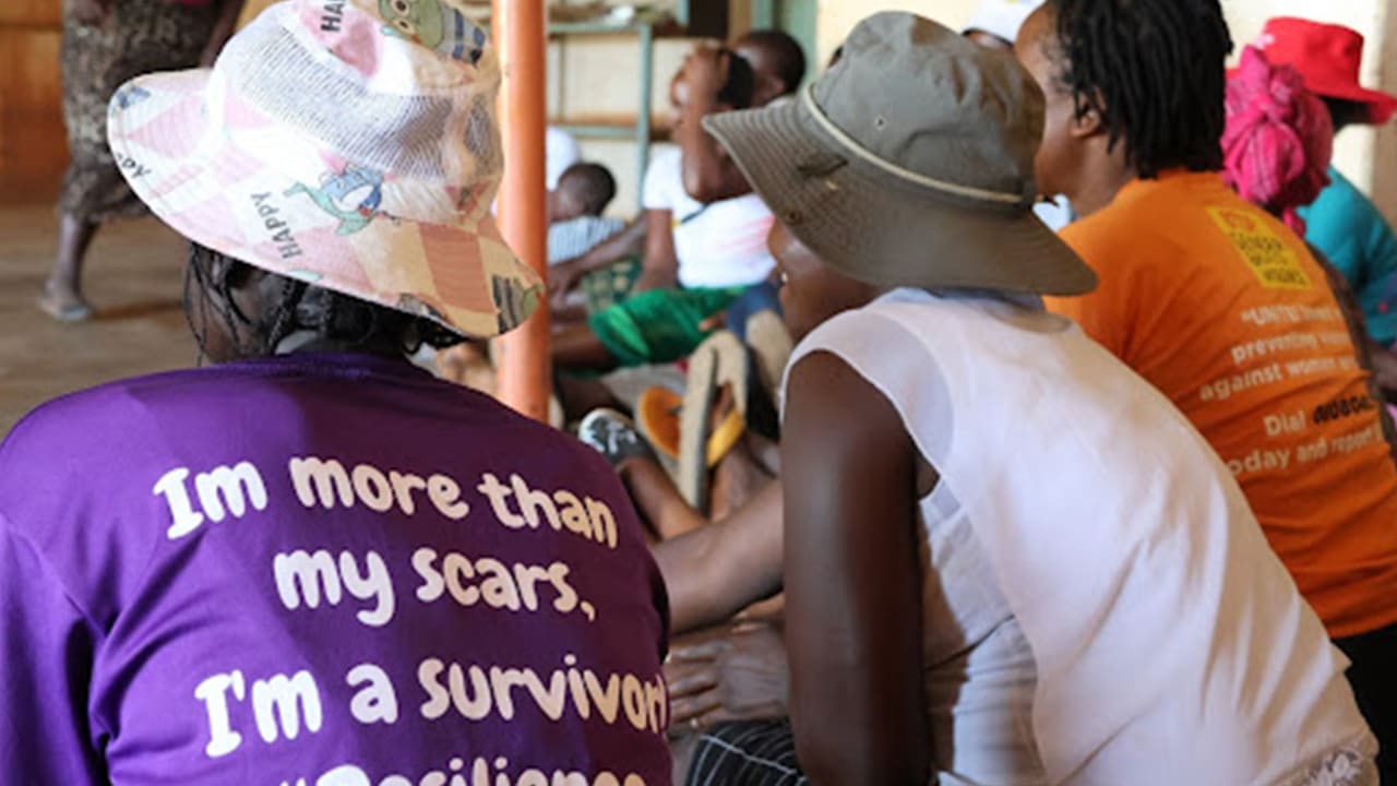 Woman wearing a purple T-shirt with the message: ‘I’m more than my scars, I’m a survivor. #Resilience’ sitting in a group meeting in Zimbabwe. 