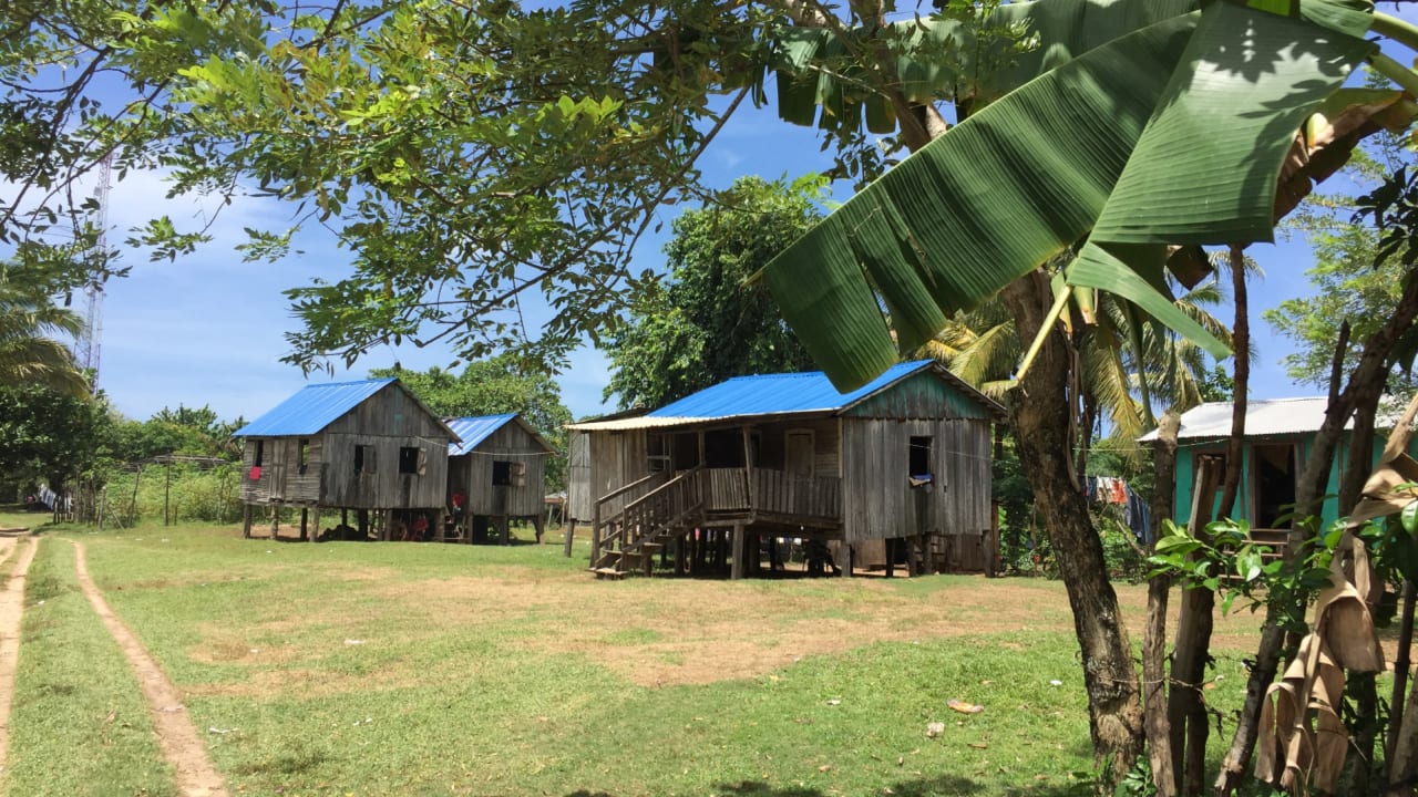 Communauté rurale avec des maisons sur pilotis aux toits bleus.