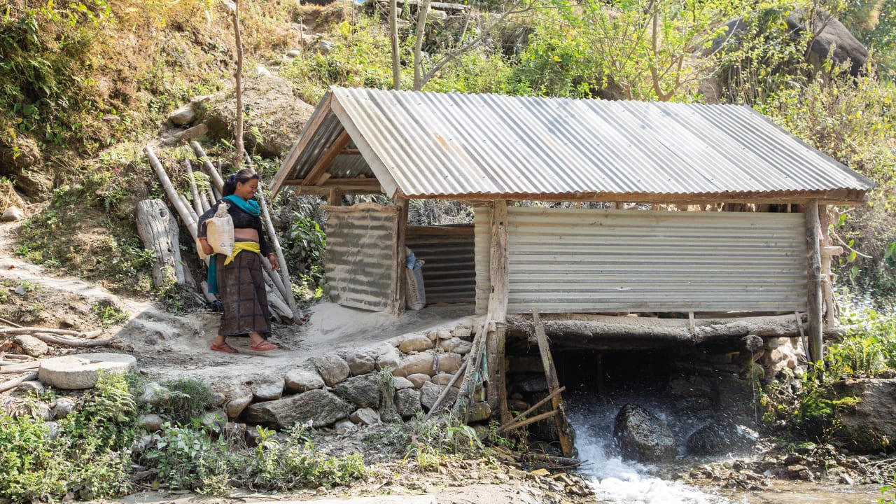 Une femme dénommée Phul Kumari apporte du grain à un moulin alimenté par l’eau provenant de la microcentrale hydroélectrique située plus haut.