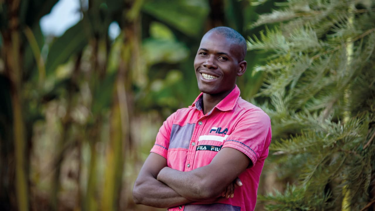 Un jeune homme burundais, vêtu d'un polo rose, sourit à l'objectif 