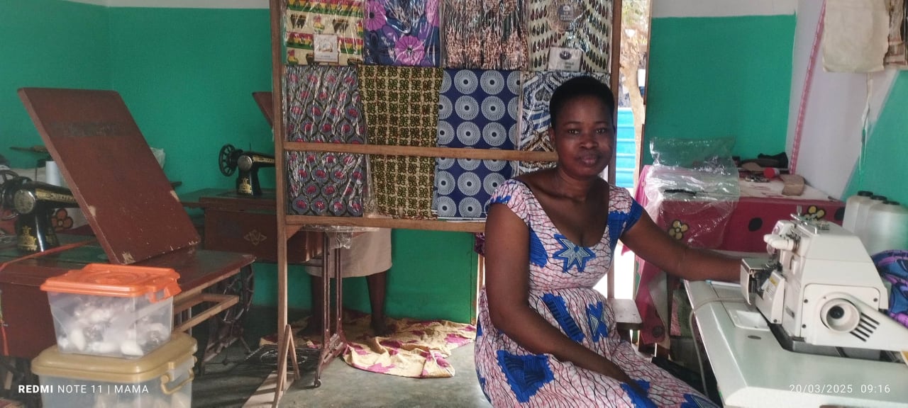 Au Togo, une femme est assise dans son atelier de couture, devant sa machine à coudre.