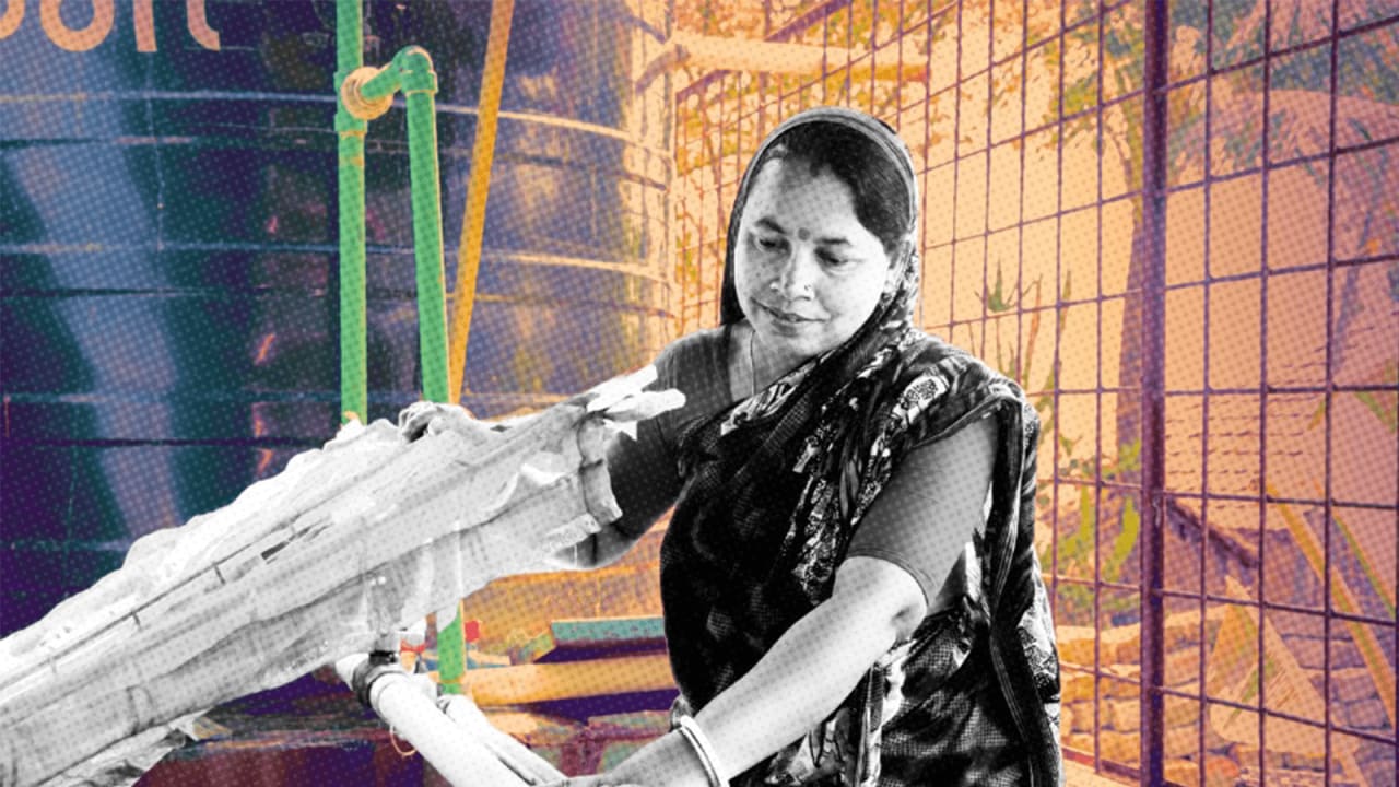 A woman, who wears a traditional dress, lifts up the lid of a machine in a water plant