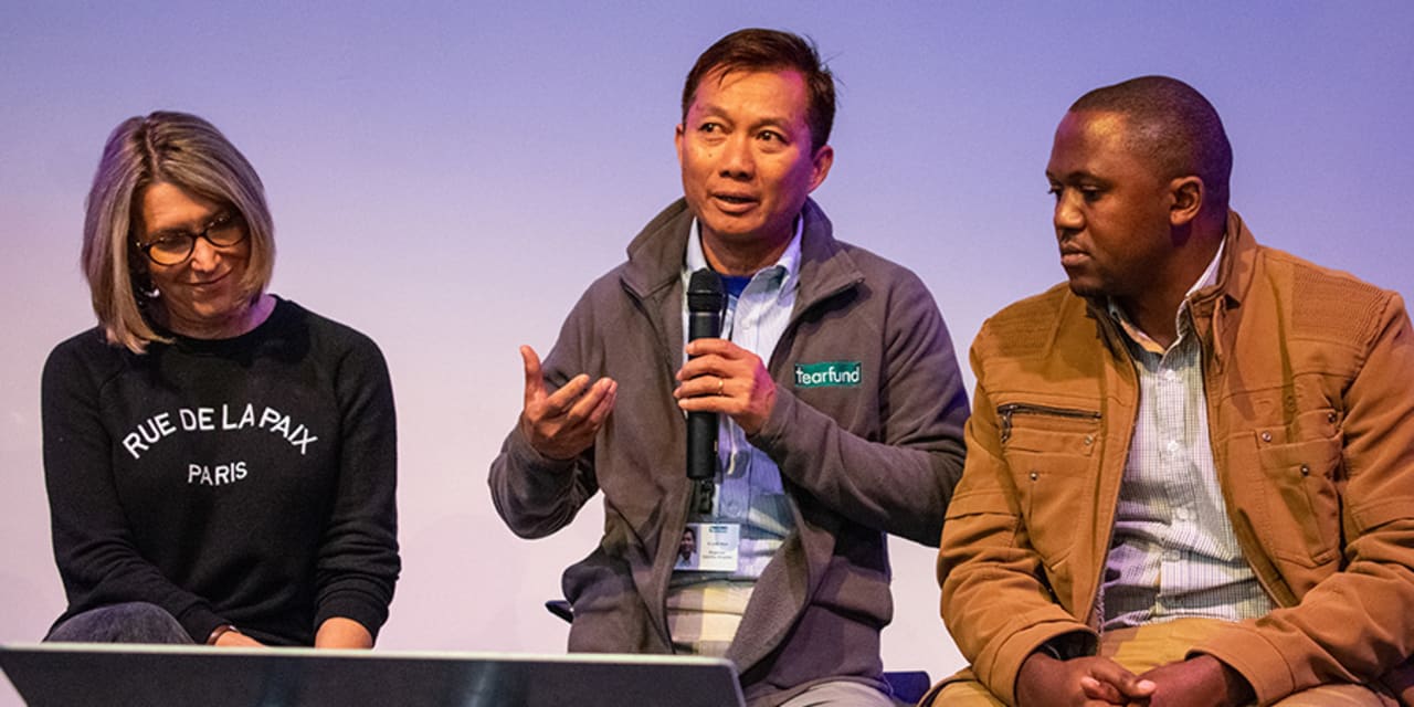 A woman and two men in conversation as a part of a panel discussion at Tearfund's Staff Conference 2019.