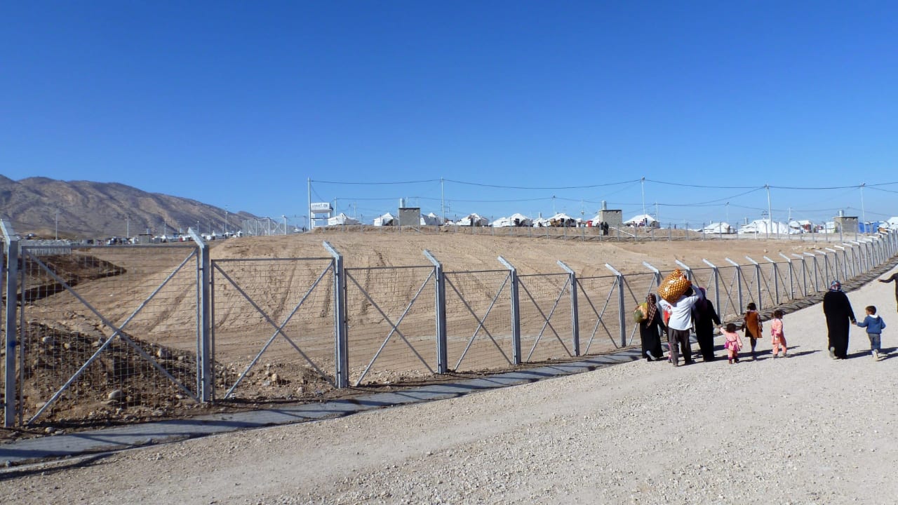 Syrian refugees return from a clothing distribution at Zelikan camp in Ninewa, Iraq. 