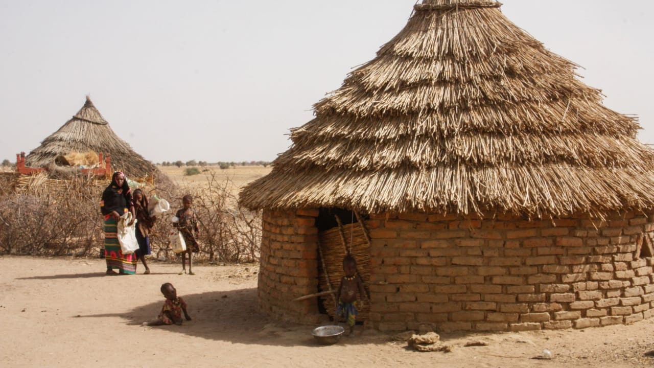 Une mère et ses enfants à l'extérieur d’une habitation dans un village rural du Tchad.