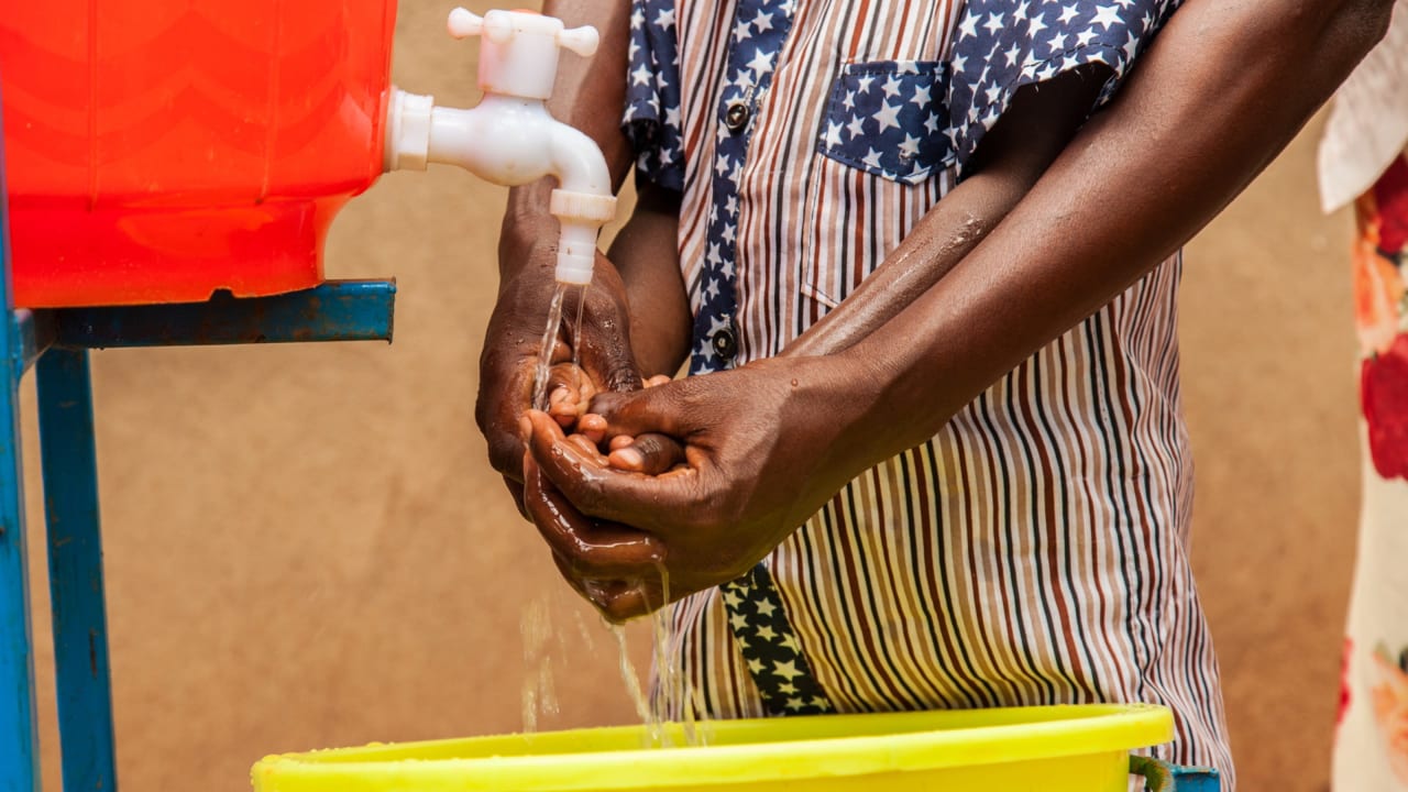 A mother teaches her child how to wash their hands in Riyakarenzi village, Eastern Rwanda.