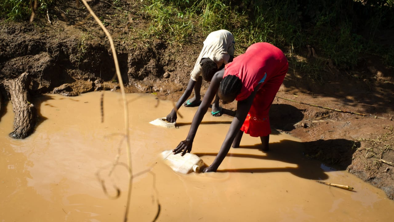 A woman collects water for irrigation purposes in Apada returnee camp in South Sudan.