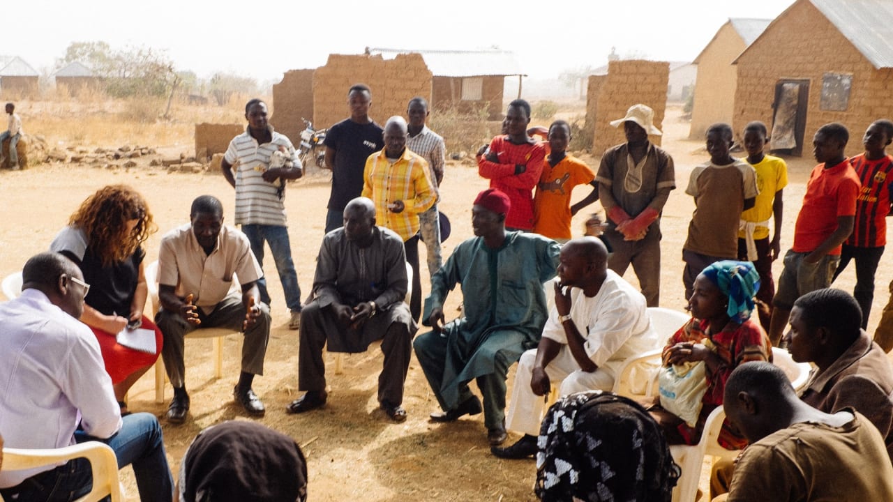 Un grupo de personas de la comunidad sentadas en círculo sostienen un debate como parte del Programa de Movilización de la Iglesia y de la Comunidad en Nigeria