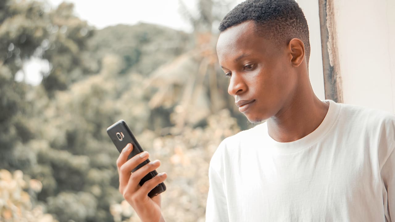 Um homem olha para o seu telefone celular