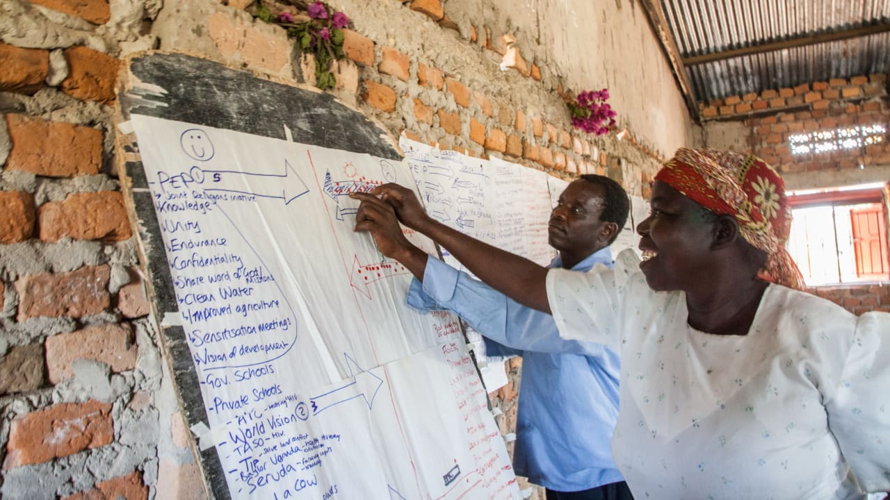 Un homme et une femme d’Ouganda devant un tableau blanc passent en revue les forces et les défis auxquels ils sont confrontés.