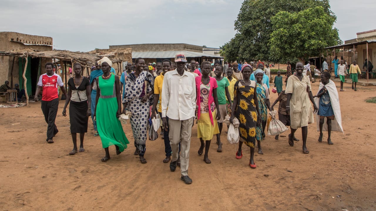 Women with food vouchers walk to the market to receive their food items from local vendors in South Sudan