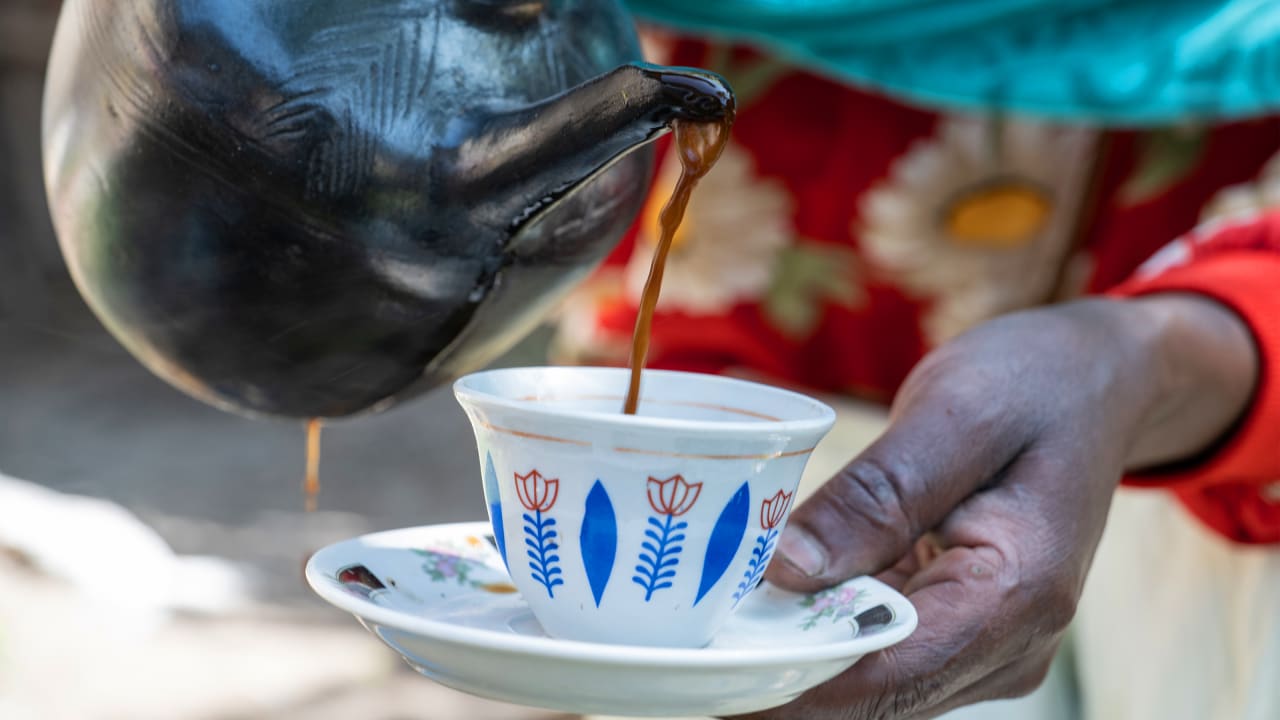 Coffee being poured from a clay pot into a cup