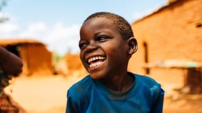 Boy smiling and looking to the left of the camera.