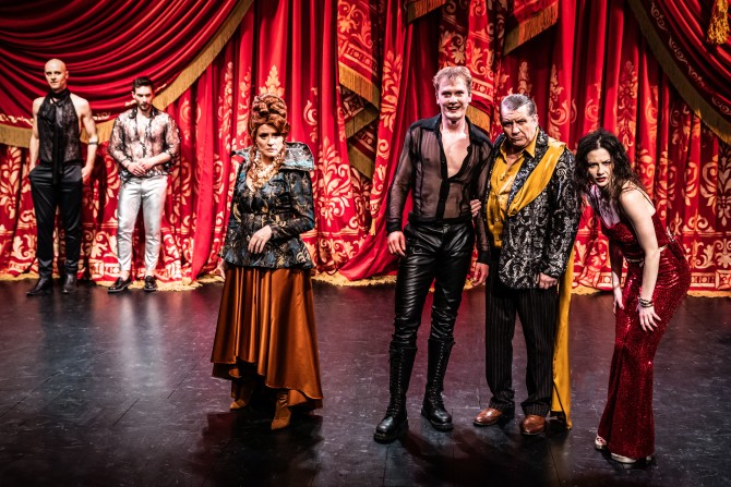 Na scenie w rzędzie stoją od prawej: Iza, Król, Książę Filip(Robert Ciszewski), Królowa. W tle jeszcze dwóch mężczyzn. Spoglądają przed siebie, wypatrują. Filip uśmiecha się, reszta skwaszona.