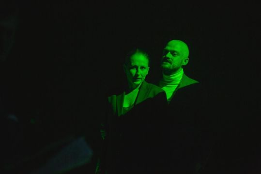 Z mroku wyłaniają się popiersia Nathalie (Katarzyna Dałek) i Steve’a (Michał Jaros). Są oświetleni intensywnym, zielonym światłem.